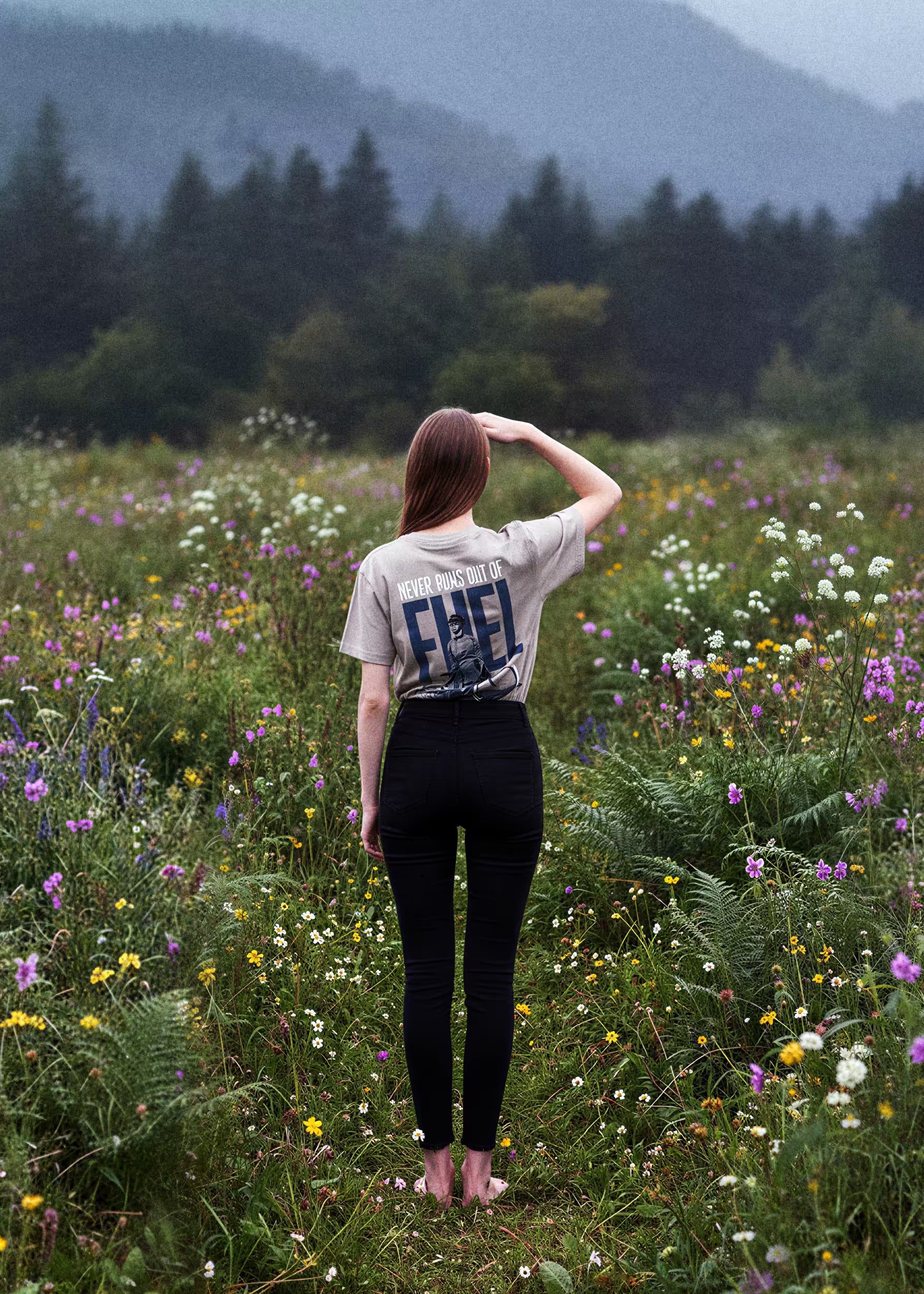 Modelo femenina con camiseta mocca Never Runs Out of Fuel en prado de flores silvestres — serigrafía trasera Crystal Peppers