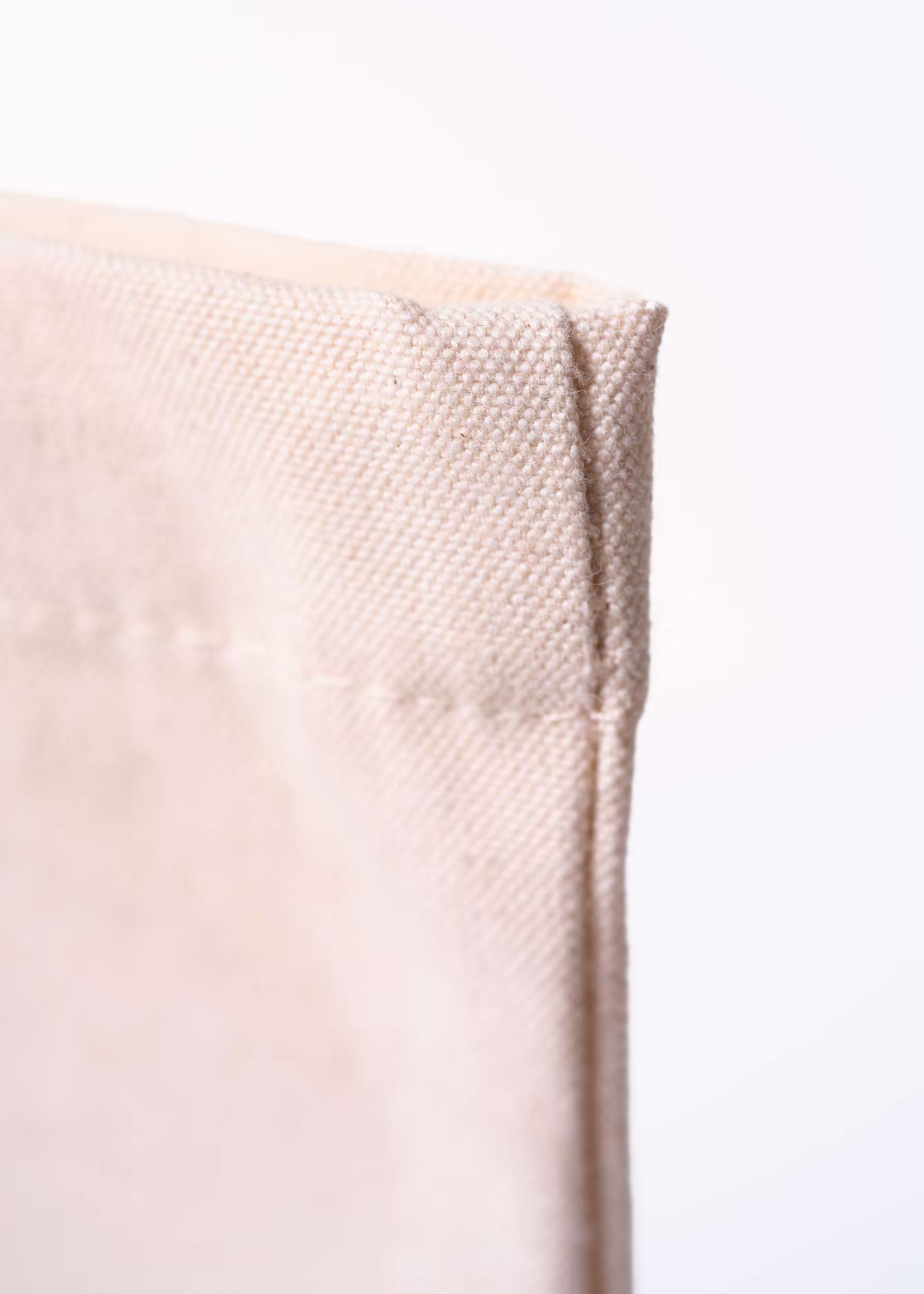 Macro textura esquina superior del algodón orgánico natural del tote bag Arena Roja — trama del lienzo 340 g/m²