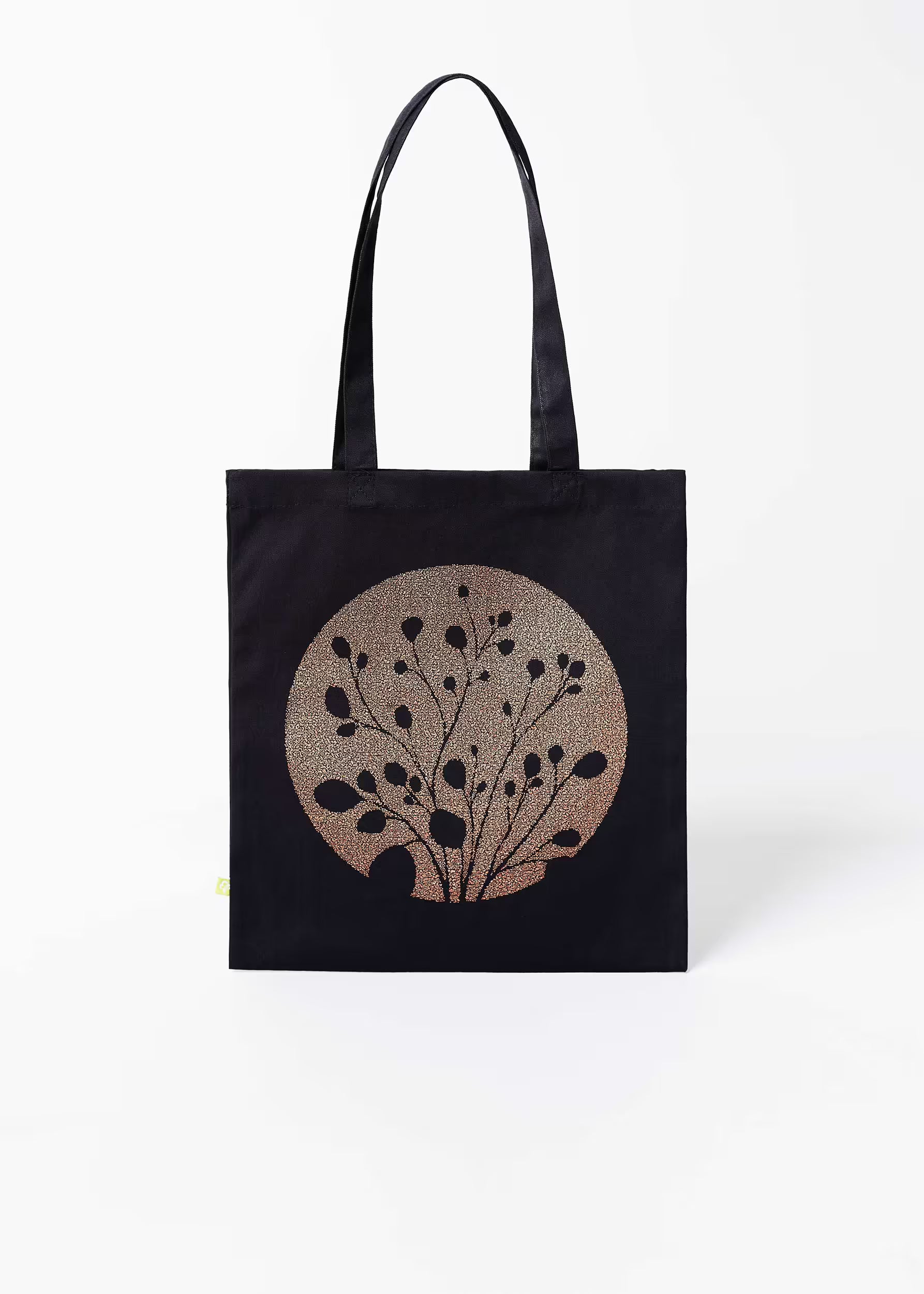 Tote bag Carbón Cobre Crystal Peppers — vista frontal con motivo botánico serigrafiado en cobre sobre fondo negro, etiqueta ecológica verde