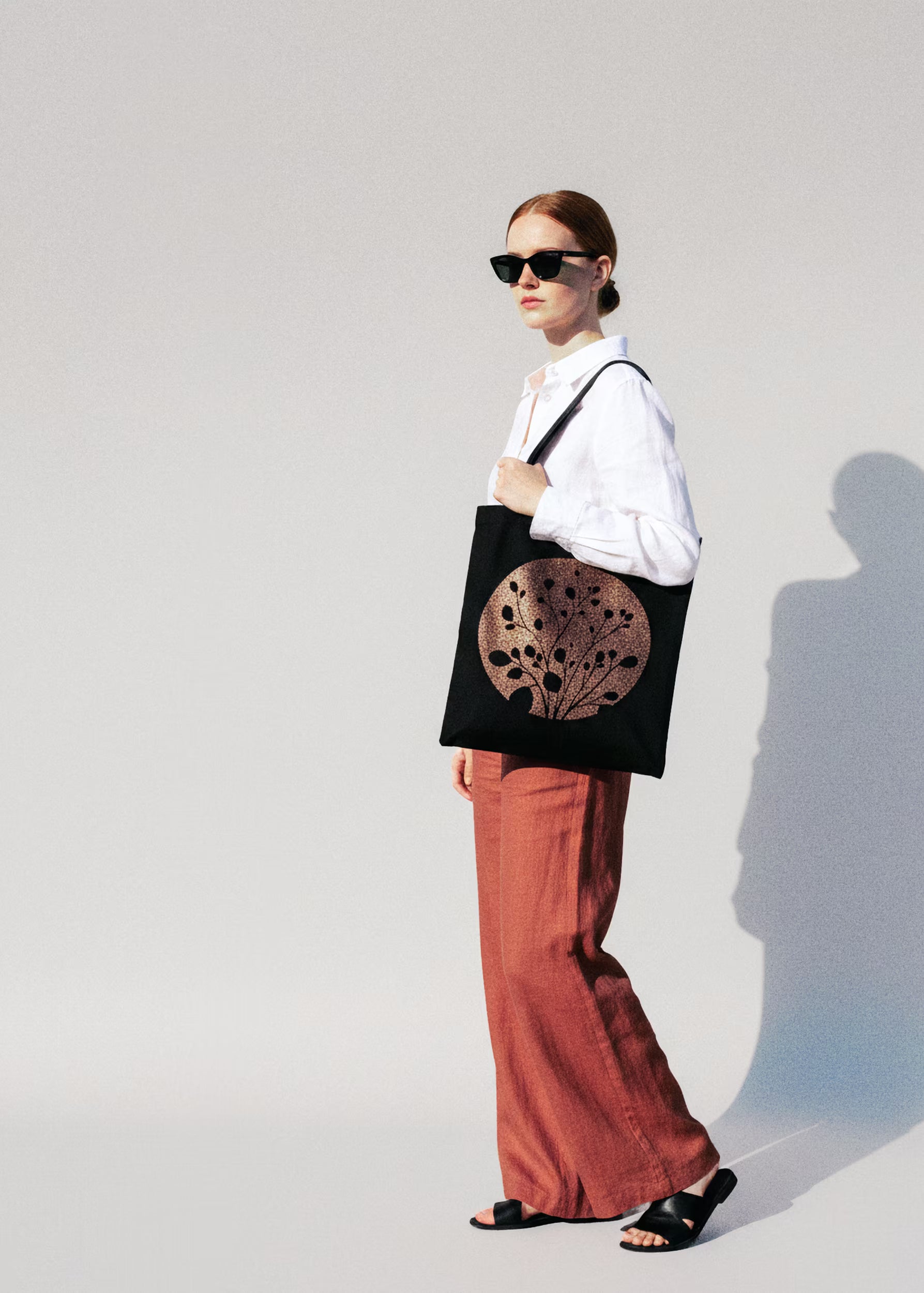 Modelo con tote bag Carbón Cobre al hombro, camisa blanca y pantalón terracota — colección Sol y Sombra Crystal Peppers