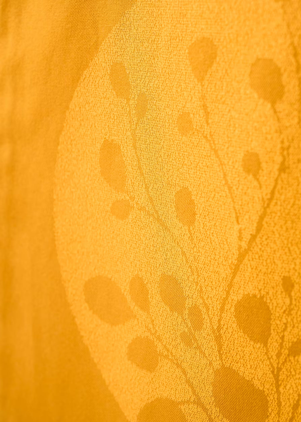 Macro de la serigrafía tono sobre tono del tote bag Gold Nugget — motivo botánico amarillo sobre ocre, tinta ecológica