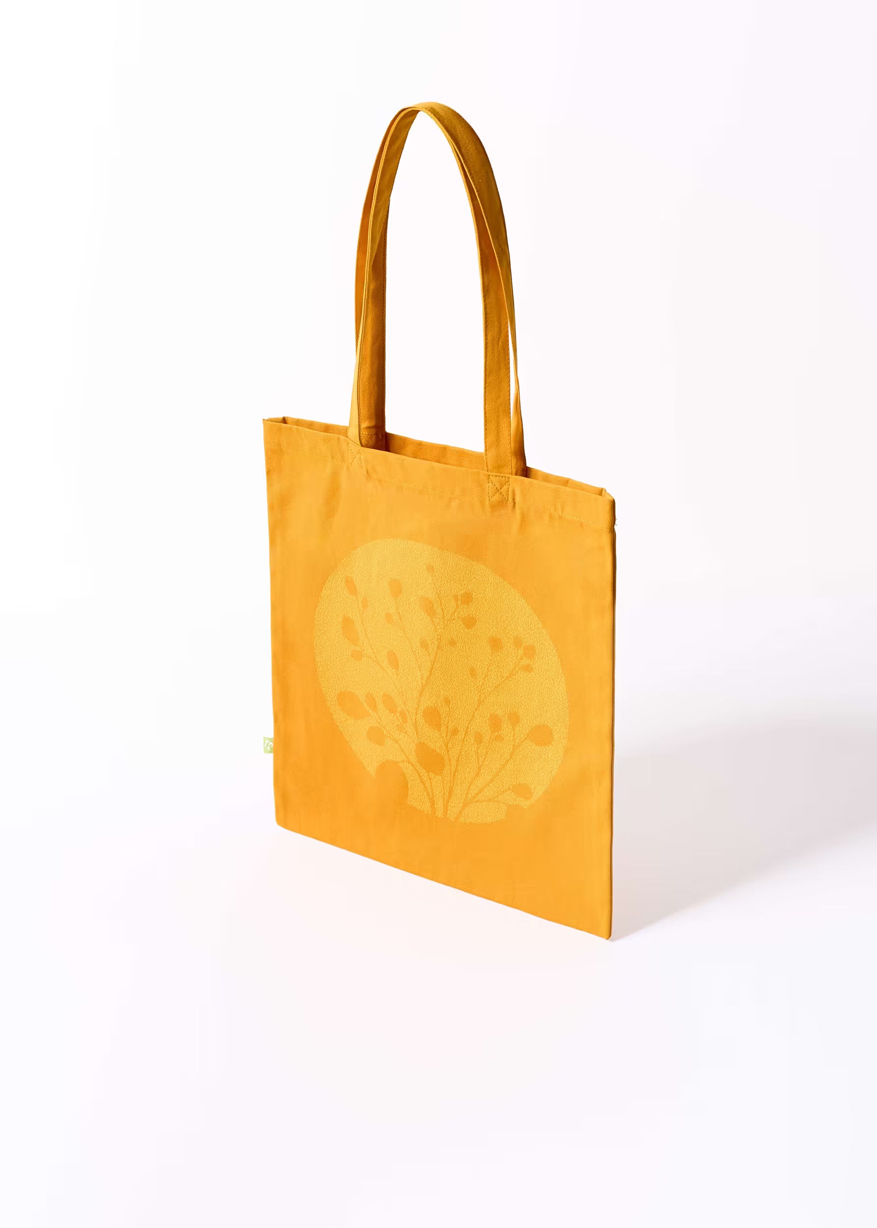 Tote bag Gold Nugget Crystal Peppers — vista tres cuartos, serigrafía amarilla sobre ocre oscuro, etiqueta ecológica verde