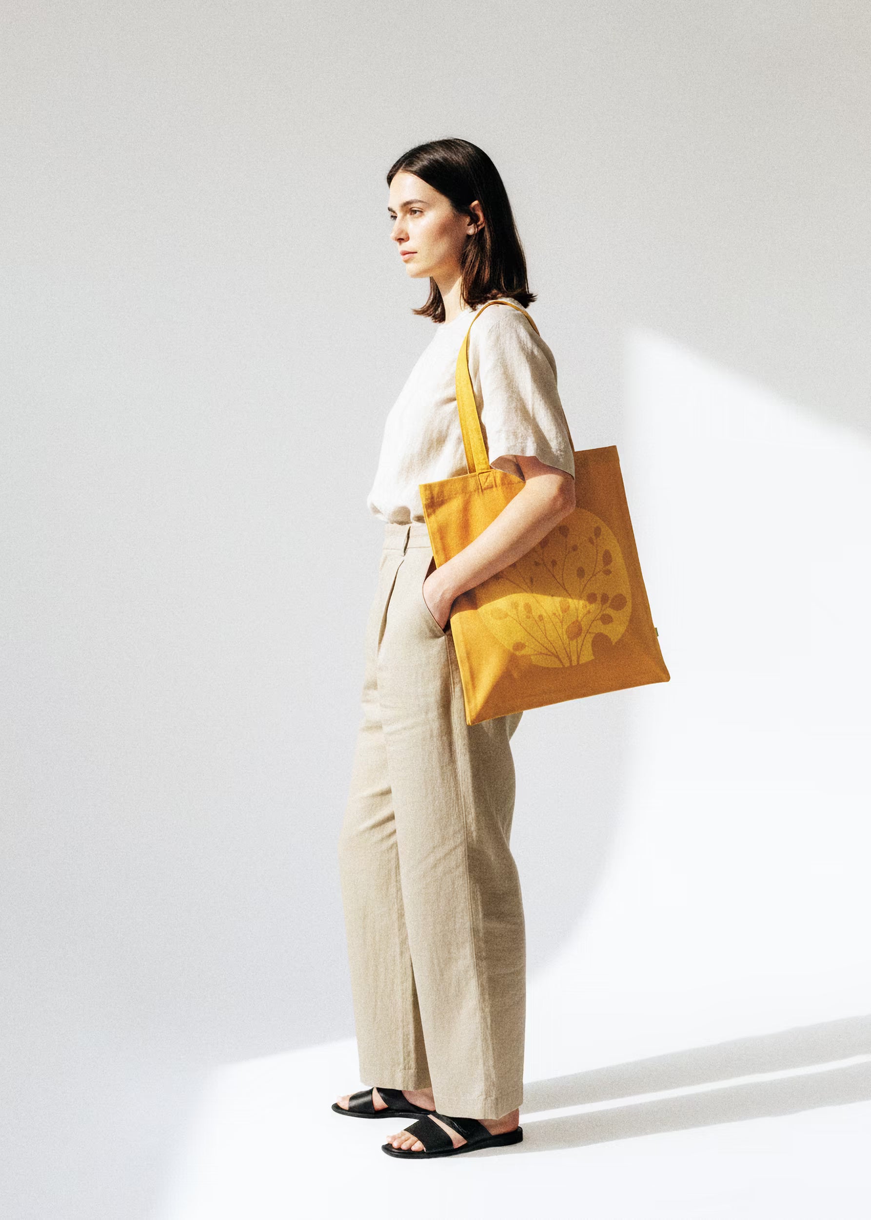 Modelo con tote bag Gold Nugget al hombro, look lino beige — colección Sol y Sombra Crystal Peppers